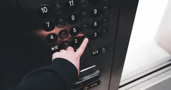 Finger drückt eine Etagentaste auf dem Bedienpanel eines Aufzugs