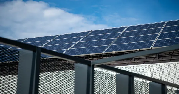 Solarmodule auf einem Dach, im Vordergrund das Metallgeländer eines Balkons