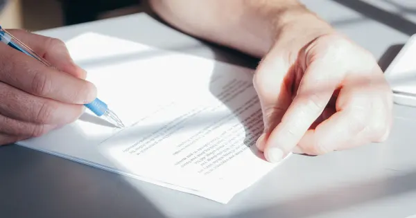 Nahaufnahme einer Person, die einen Vertrag mit Kugelschreiber unterschreibt