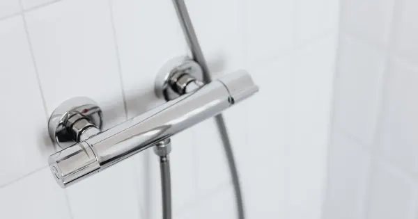 Moderne Chrom-Duscharmatur mit Handbrause an einer weiß gefliesten Wand