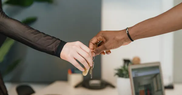Zwei Personen übergeben sich in einem Büro die Schlüssel bei einem Immobiliengeschäft